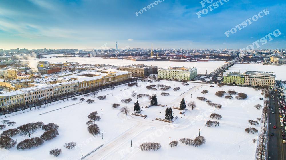 На фотографии изображено Марсово поле, укрытое снежным покровом. Центральная часть поля украшена Вечным огнём и скульптурами. На заднем плане виднеются архитектурные памятники и река Нева, создавая уникальный зимний городской пейзаж. Марсово поле — одно из старейших общественных пространств Санкт-Петербурга.